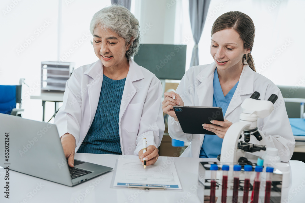 Scientists are doing research in a medical laboratory. Foreground researcher using a microscope Scientists are doing research in a medical laboratory. Foreground researcher using a microscope