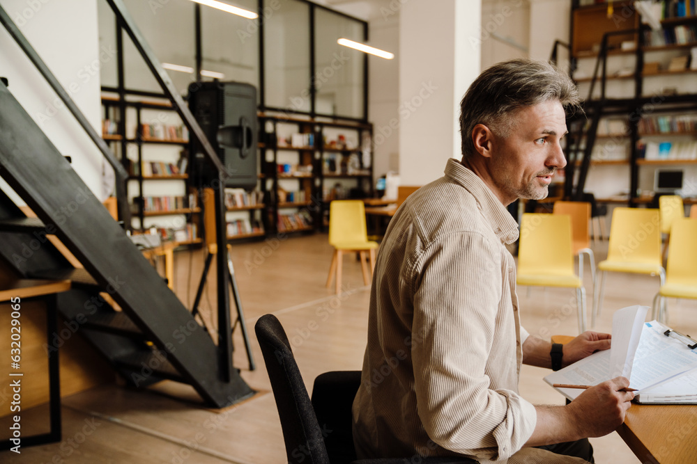 Adult man talking to someone while sitting in library Adult man talking to someone while sitting in library