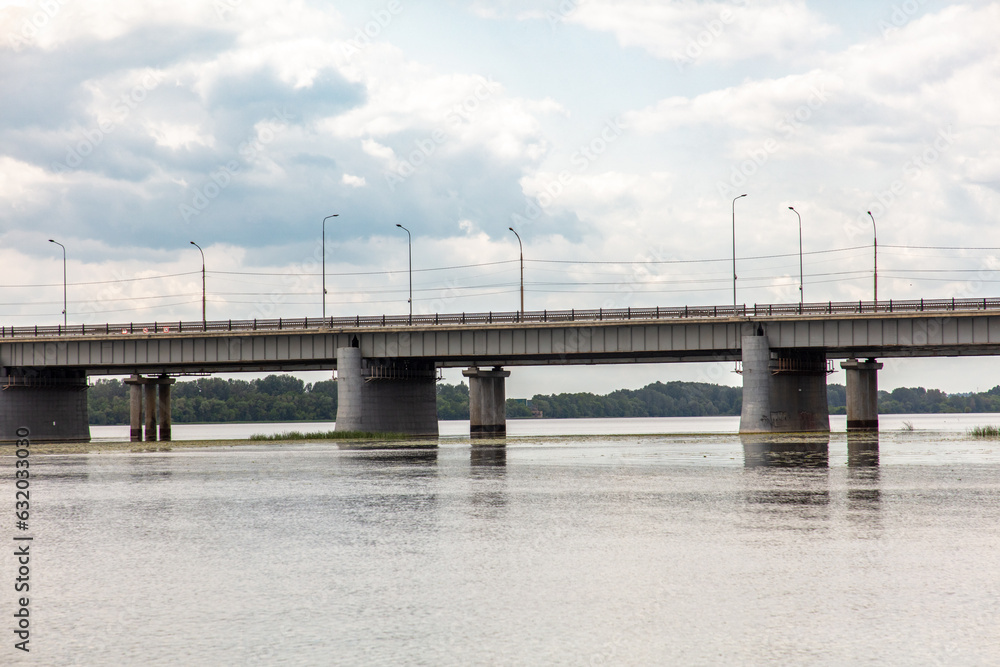 Concrete bridge across the river against the backdrop of clouds with the sky