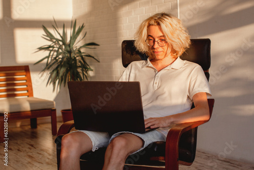 Smiling guy is browsing at his laptop at home