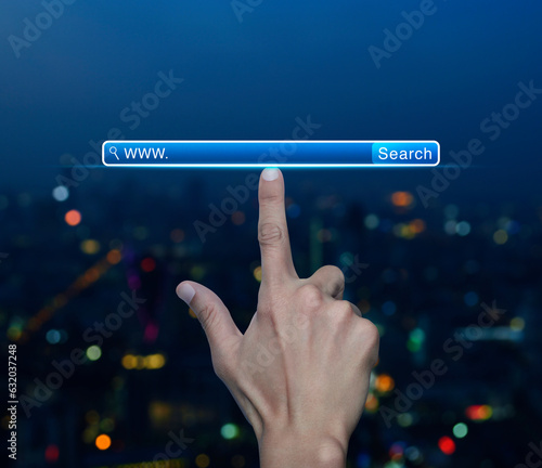 Hand pressing search www button over blur colorful night light modern city tower and skyscraper, Searching system and internet concept