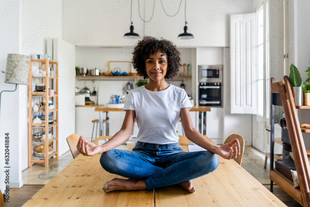 Portrait of smiling woman in yoga pose on table at home Portrait of smiling woman in yoga pose on table at home