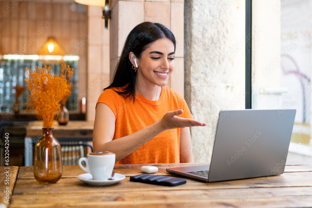 Young freelancer gesturing on video call through laptop sitting in cafe Young freelancer gesturing on video call through laptop sitting in cafe