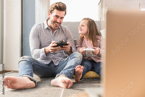 Young man and little girl playing computer game with gaming console photo