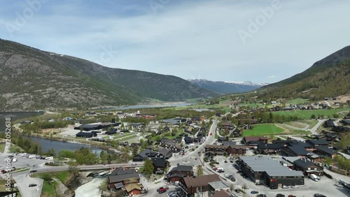 Rising aerial revealing beautiful Lom and Fossbergom in Norway - Stunning landscape with busy street and snow capped mountain background photo