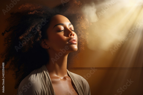 A woman of color seated in a comfortable yoga pose her eyes closed in meditation while the sun casts a warm shining light on her serene