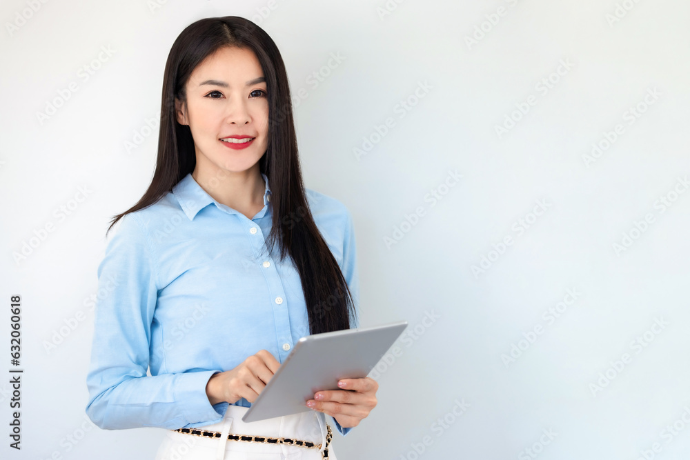 Asian businesswoman smiling and holding digital tablet standing on white background. Happy business woman using tablet on copy space light background. Business,finance, employment,female successful.. Asian businesswoman smiling and holding digital tablet standing on white background. Happy business woman using tablet on copy space light background. Business,finance, employment,female successful..