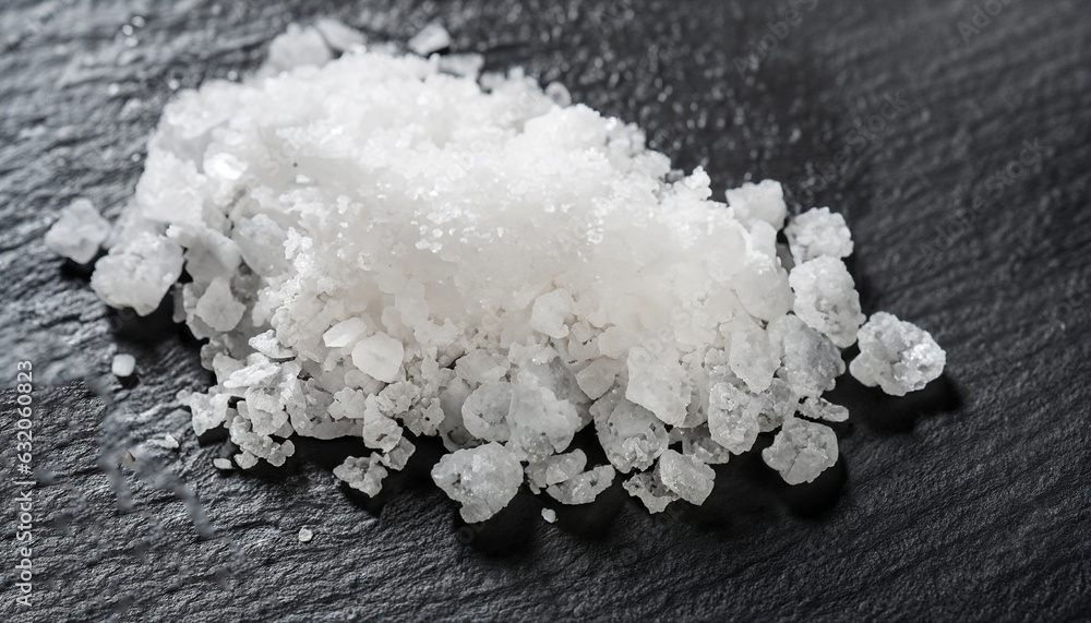 the salt crystals on black stone plate background , selective focus