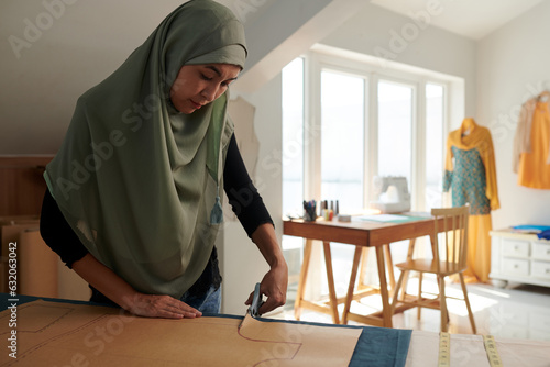 Canvas Print Muslim seamstress cutting out sewing pattern in her studio