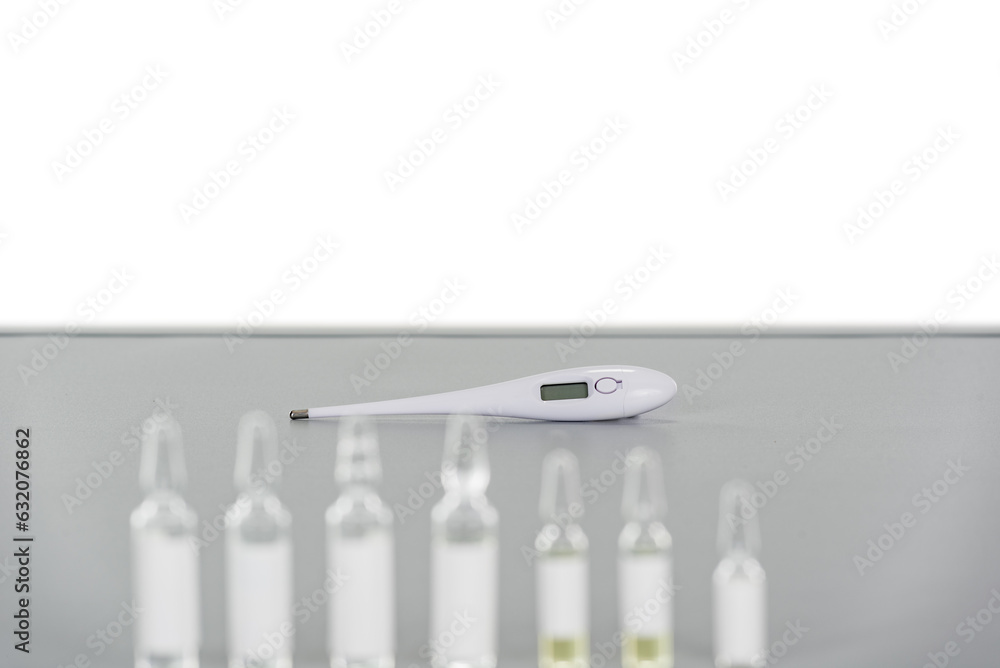 a row of standing ampoules and a white thermometer on a gray table with copy space background a row of standing ampoules and a white thermometer on a gray table with copy space background