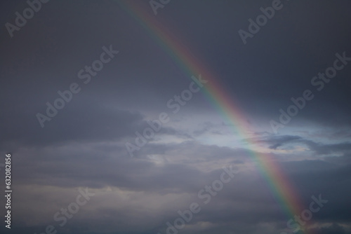 Rainbow on stormy dark sky background.