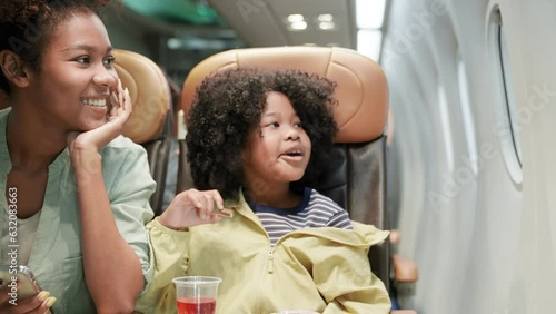 Agirl was excited to get on a plane for the first time to travel. Child looks out window of an airplane in flight. Take a photo.Teenage flying in airplane. Talking while waiting to landing on runwa