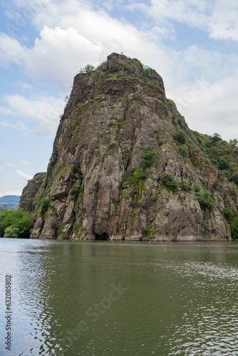 Lake and huge rock. Beautiful nature, the river flows downhill. Green forests and mountains