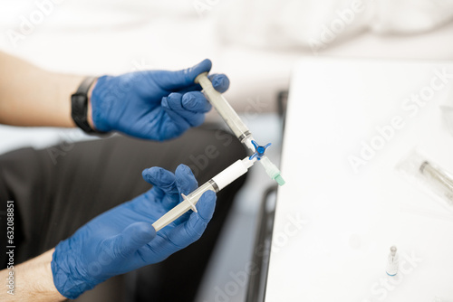 Phlebology doctor prepares special solution in syringe for sclerotherapy, close-up on syringe. Concept of medical treatment of varicose veins