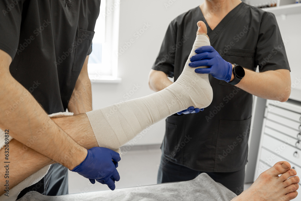 Two medical workers make a bandage on patient's leg in the trauma ...
