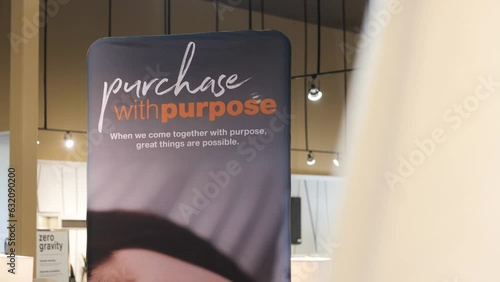 A 4K Panning Shot of A Retail Furniture Store Location Financing Promotional Banner Financing Credit Card Sign 'Purchase with Purpose' Orange and Blue Advertisement Background with Hanging Lights photo