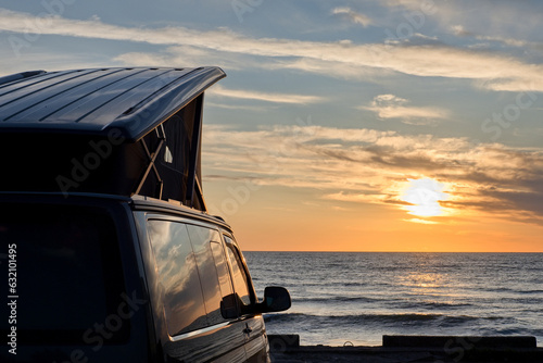 Camper van is stand on camping place on sea coast. Beautiful seascape.