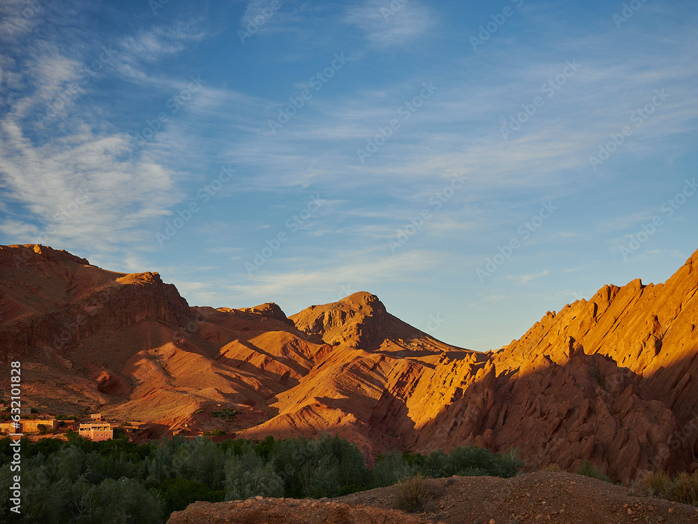 Naklejka premium Oasis with lush and green vegetation in the dry and arid deserted region in a desert landscape in the mountains of Morocco.