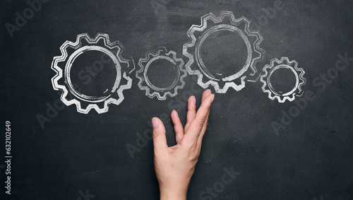 Foto Chalk-drawn gears and a female hand on a black chalkboard, concept of teamwork