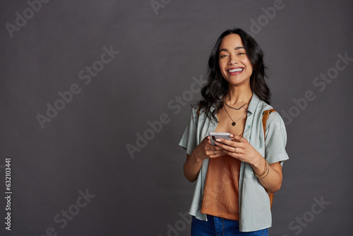Multiethnic young woman using smartphone on grey wall