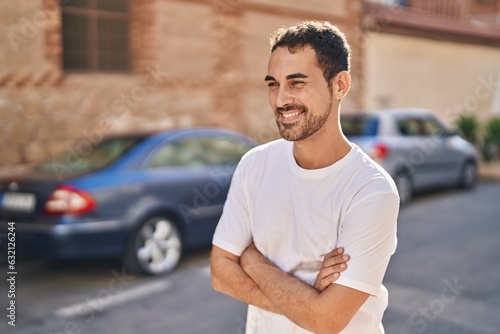 Young hispanic man standing with arms crossed gesture at street
