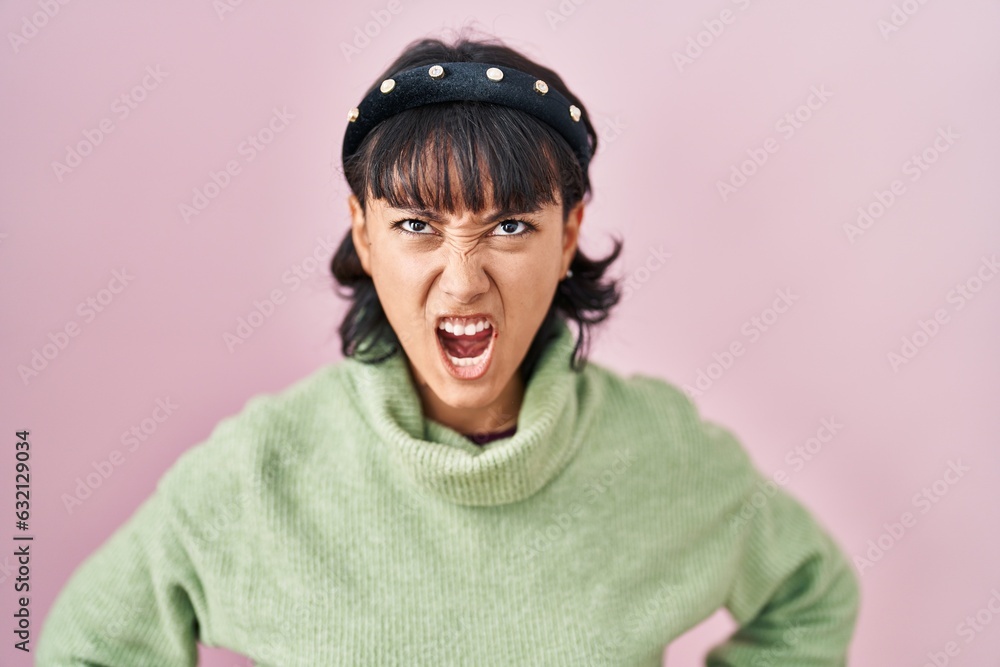 Young beautiful woman standing over pink background angry and mad screaming frustrated and furious, shouting with anger. rage and aggressive concept. Young beautiful woman standing over pink background angry and mad screaming frustrated and furious, shouting with anger. rage and aggressive concept.