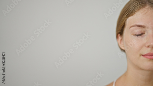 Young blonde woman standing with serious face and close eyes over isolated white background