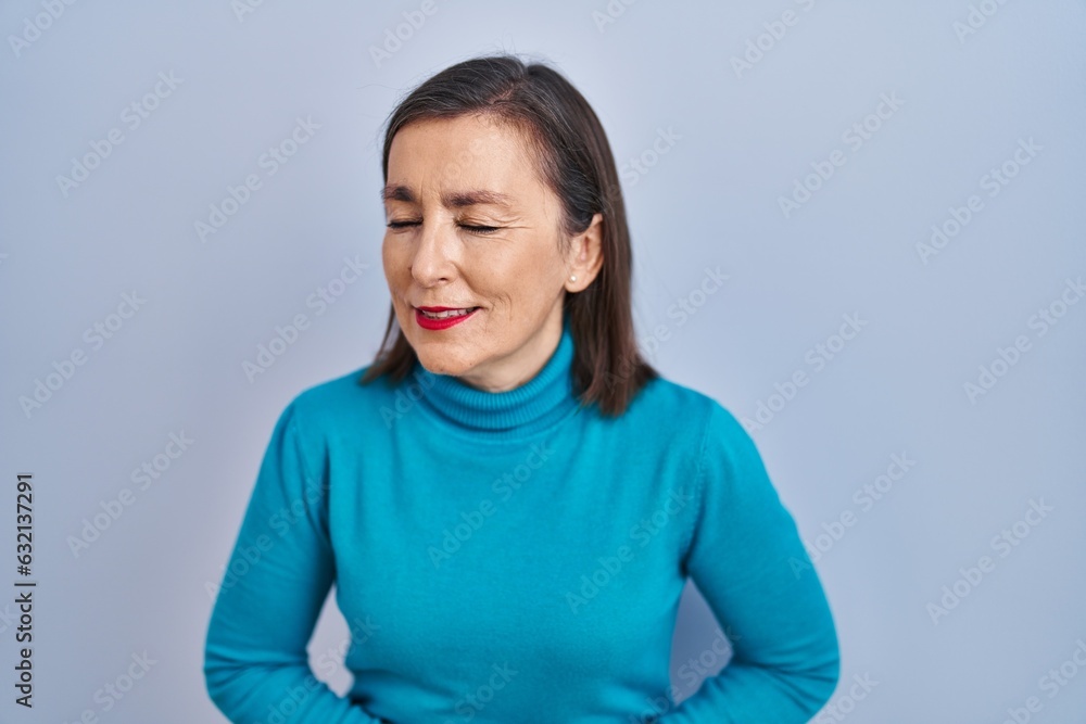 Middle age hispanic woman standing over isolated background with hand on stomach because nausea, painful disease feeling unwell. ache concept. Middle age hispanic woman standing over isolated background with hand on stomach because nausea, painful disease feeling unwell. ache concept.