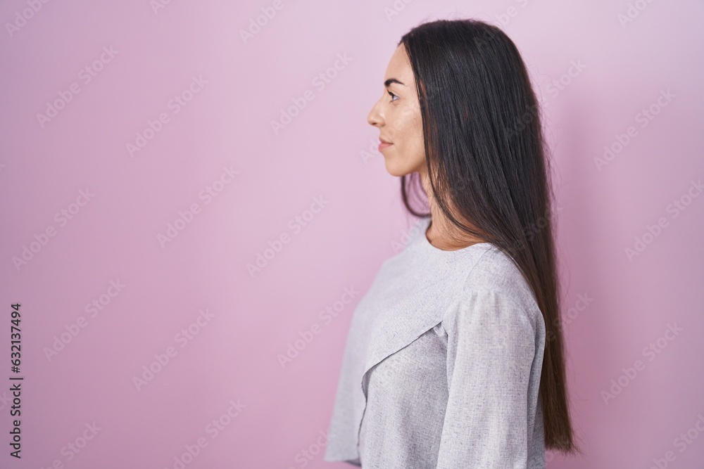 Young brunette woman standing over pink background looking to side, relax profile pose with natural face with confident smile. Young brunette woman standing over pink background looking to side, relax profile pose with natural face with confident smile.