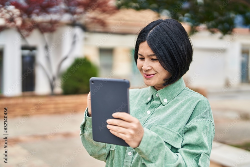 Fototapeta premium Young chinese woman smiling confident drawing on touchpad at park
