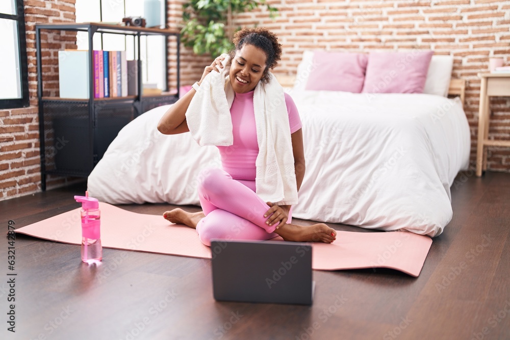 African american woman using towel sitting on yoga mat at bedroom African american woman using towel sitting on yoga mat at bedroom