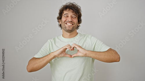 Young hispanic man smiling confident doing heart gesture with hands over isolated white background photo