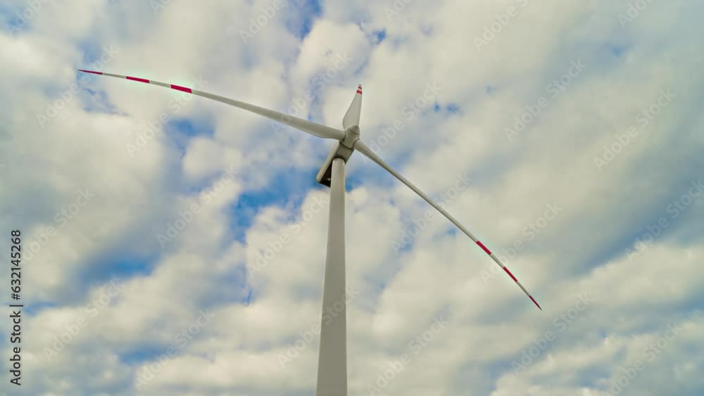 Energy farm with windmill and wind turbine generators against blue skyline and moving clouds time lapse. Electricity, ecological saving and alternative power source Energy farm with windmill and wind turbine generators against blue skyline and moving clouds time lapse. Electricity, ecological saving and alternative power source