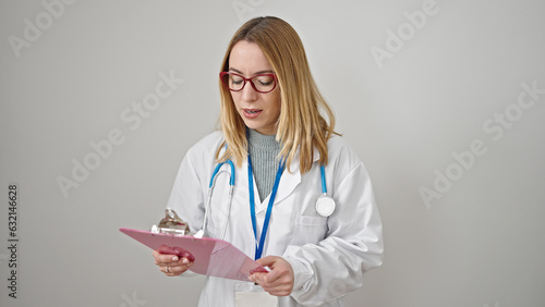 Young blonde woman doctor reading document on clipboard over isolated white background