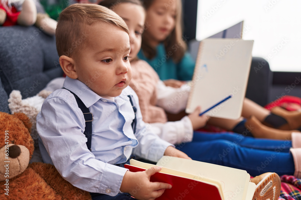 Obraz premium Group of kids drawing on notebook sitting on sofa by christmas decoration at home