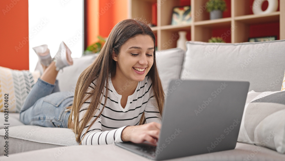Young beautiful hispanic woman using laptop lying on sofa at home Young beautiful hispanic woman using laptop lying on sofa at home