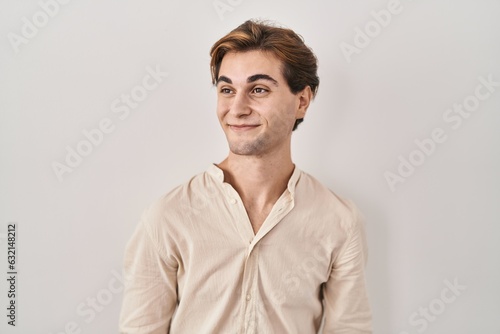 Young man standing over isolated background smiling looking to the side and staring away thinking. © Krakenimages.com