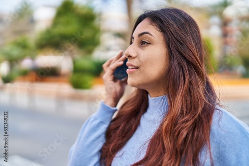 Young hispanic woman smiling confident listening audio message by the smartphone at street