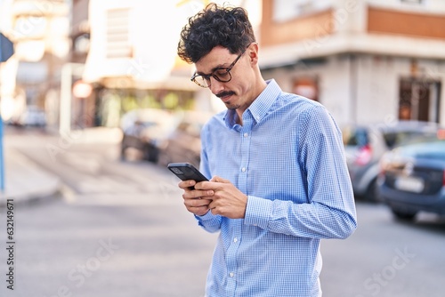 Young caucasian man using smartphone with serious expression at street