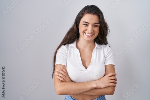 Young teenager girl standing over white background happy face smiling with crossed arms looking at the camera. positive person.