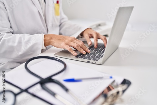 Young hispanic man doctor using laptop at clinic