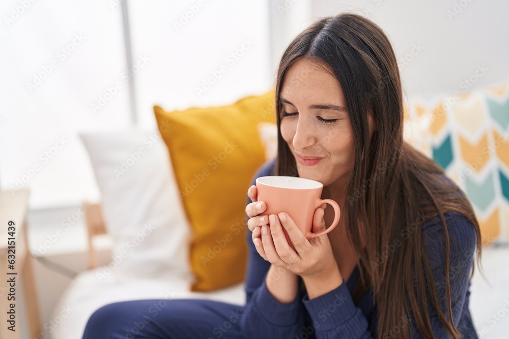 Young beautiful hispanic woman drinking cup of coffee sitting on bed at bedroom Young beautiful hispanic woman drinking cup of coffee sitting on bed at bedroom