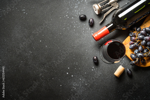 Red Wine at black background. Glass of wine, bottle and crapes. Top view with copy space.