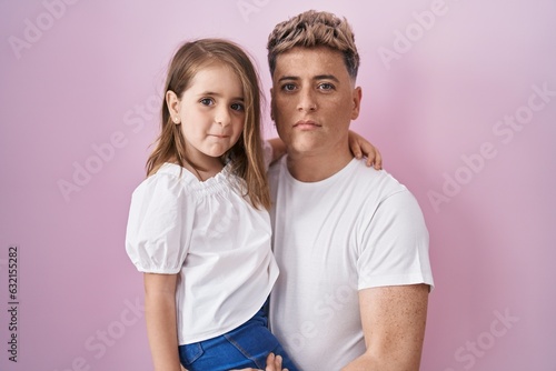 Fotografie Young father hugging daughter over pink background thinking attitude and sober e