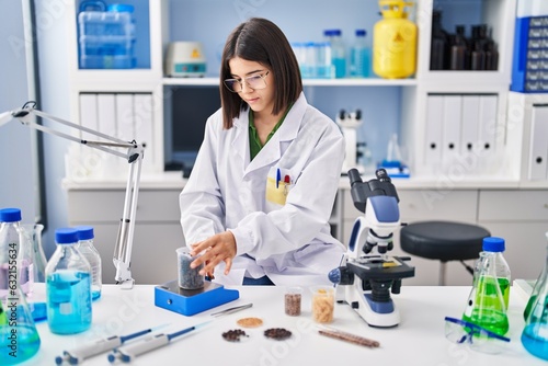 Young beautiful hispanic woman scientist weighing sample at laboratory