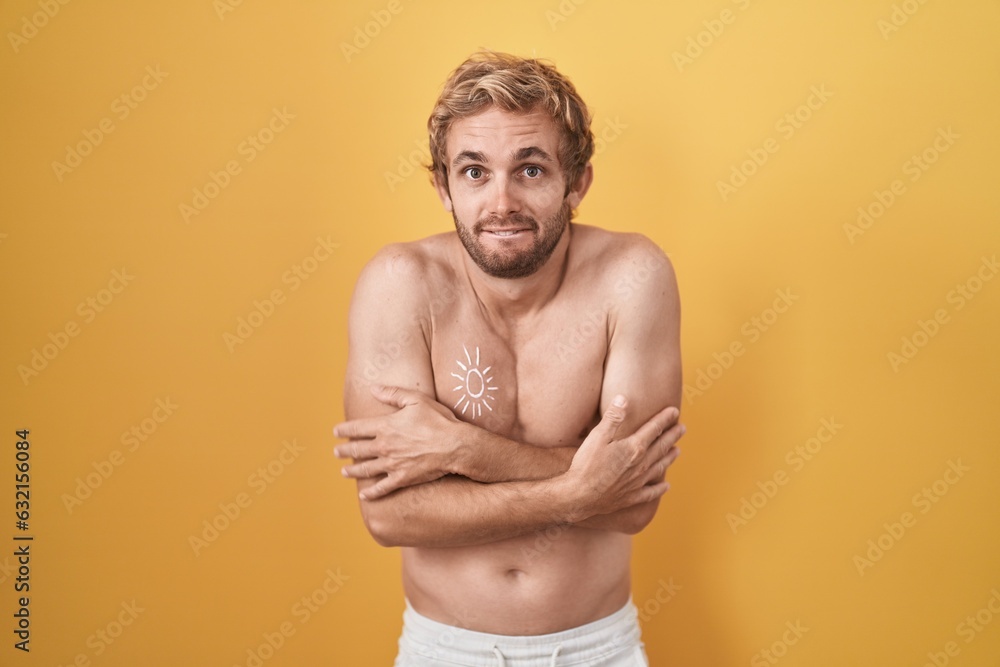 Caucasian man standing shirtless wearing sun screen shaking and freezing for winter cold with sad and shock expression on face