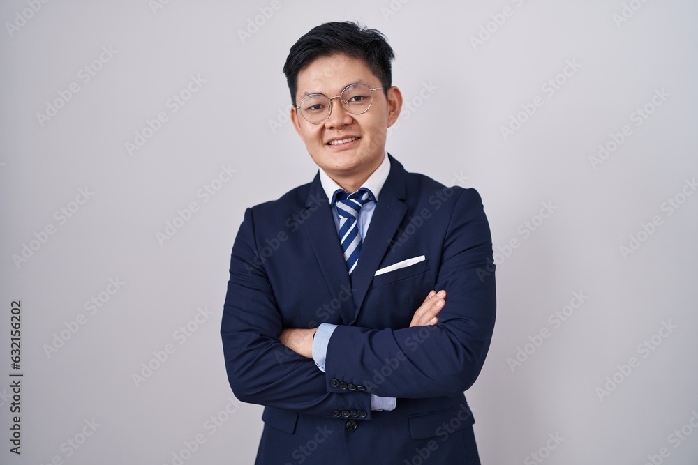 Young asian man wearing business suit and tie happy face smiling with crossed arms looking at the camera. positive person. Young asian man wearing business suit and tie happy face smiling with crossed arms looking at the camera. positive person.