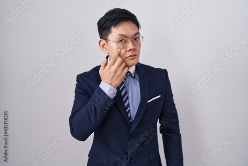 Young asian man wearing business suit and tie pointing to the eye watching you gesture, suspicious expression