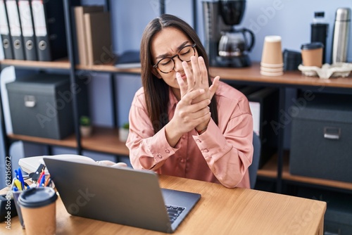 Young hispanic woman business worker suffering for hand pain at office photo