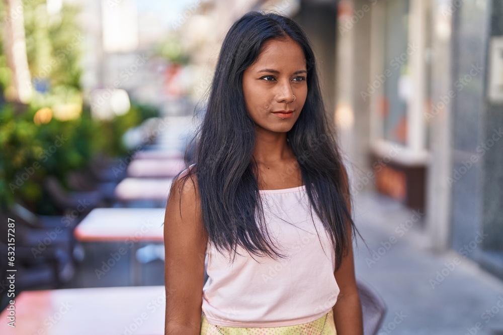 Young beautiful woman looking to the side with serious expression at street